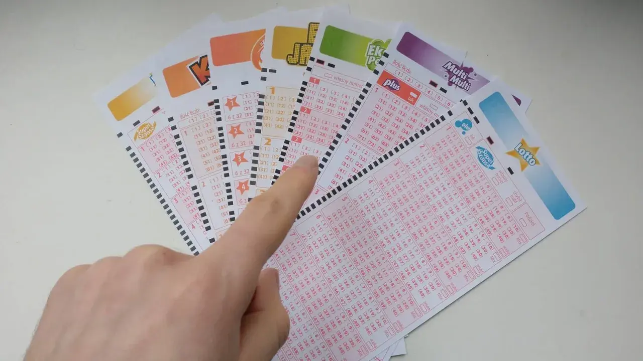 Ręka wskazuje na kupony lotto, sugerując, czy systemy do gier liczbowych mogą przewidzieć wyniki loterii.