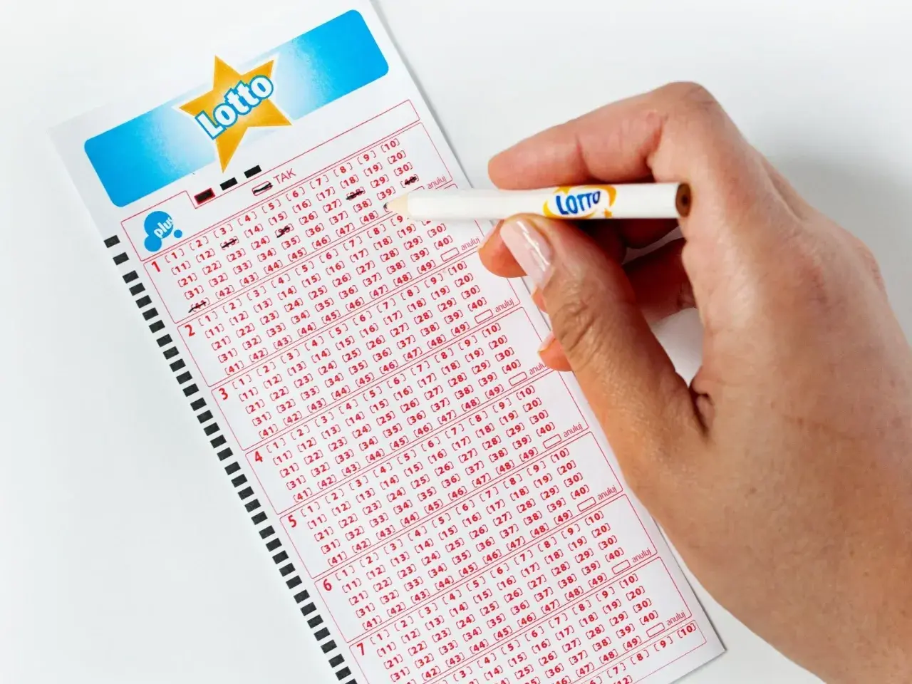 Ręka z ołówkiem zaznacza liczby na kuponie Lotto. Jak poprawnie wypełnić wniosek o loterię wizową DV do USA bez błędów?
