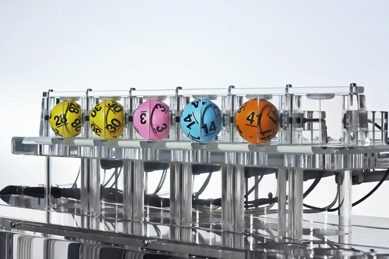 Kaskada Lotto: dlaczego zawsze losuje 12 liczb i jak sprawdzić wygraną? Kolorowe kule z numerami w maszynie losującej.