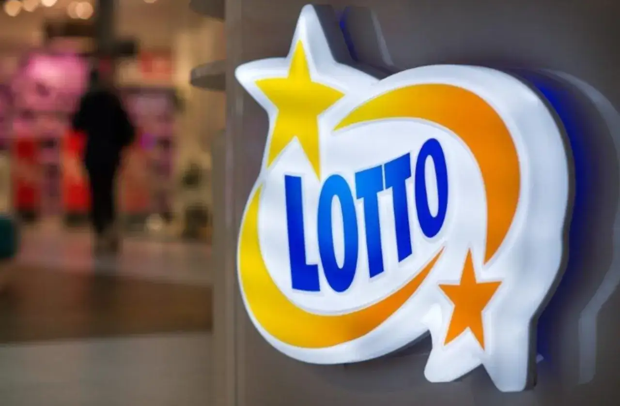 Logo LOTTO. Czy metoda chybił trafił czy skreślanie własnych liczb wygrywa częściej? W tle niewyraźna postać w sklepie.