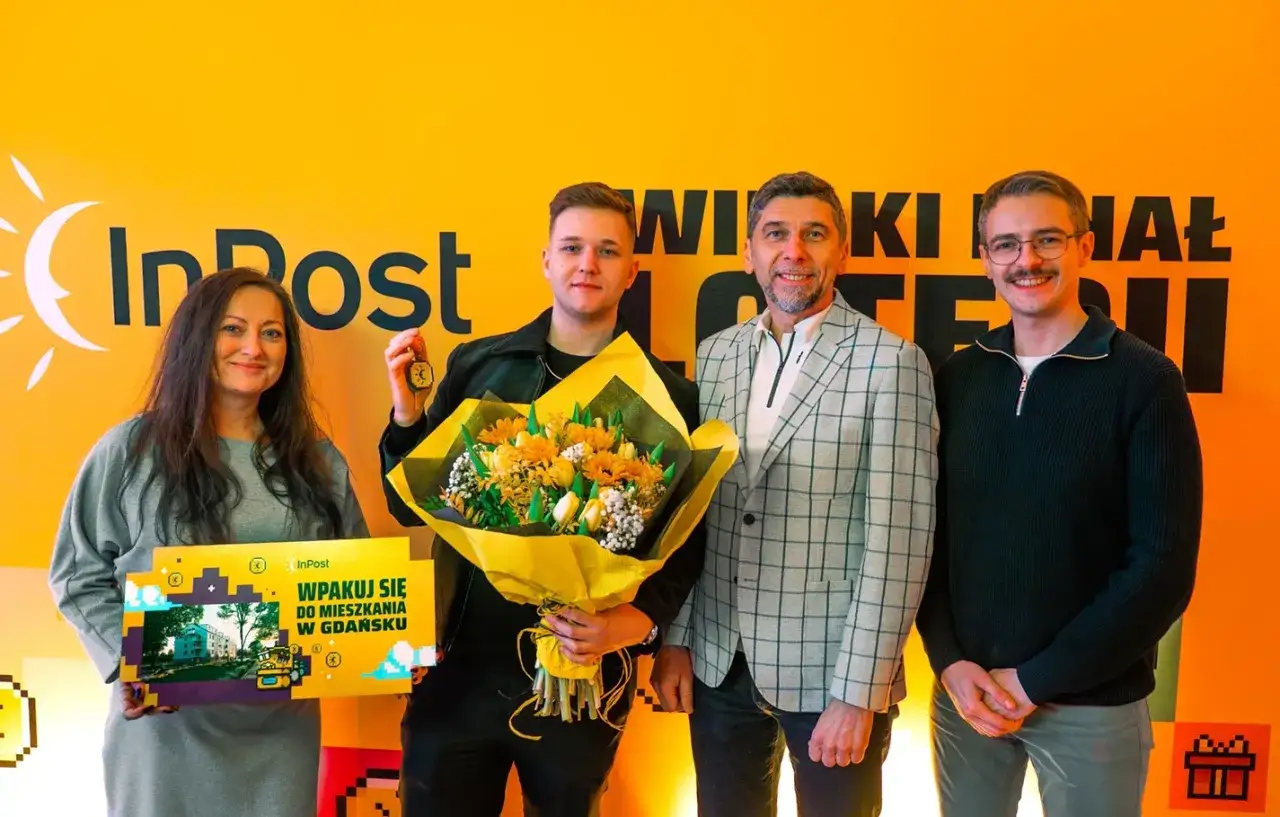 Szczęśliwy zwycięzca loterii InPost, który wygrał mieszkanie w Gdańsku, odbiera bukiet i klucze.