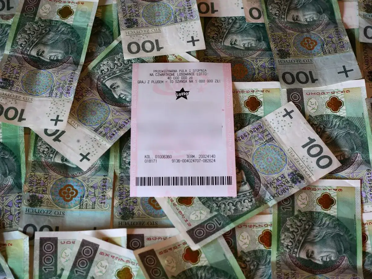 Kupon Lotto leży na stosie banknotów 100 zł. Sprawdź, jak długo ważny jest kupon lotto, by odebrać wygraną!