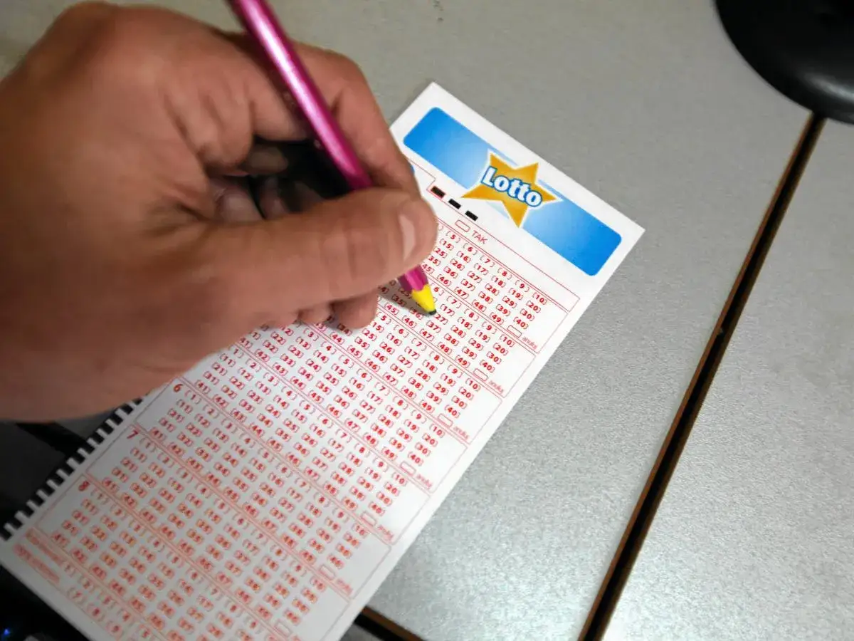Ręka z różowym długopisem zaznacza liczby na kuponie Lotto. Czas sprawdzić wyniki lotto i swój kupon!