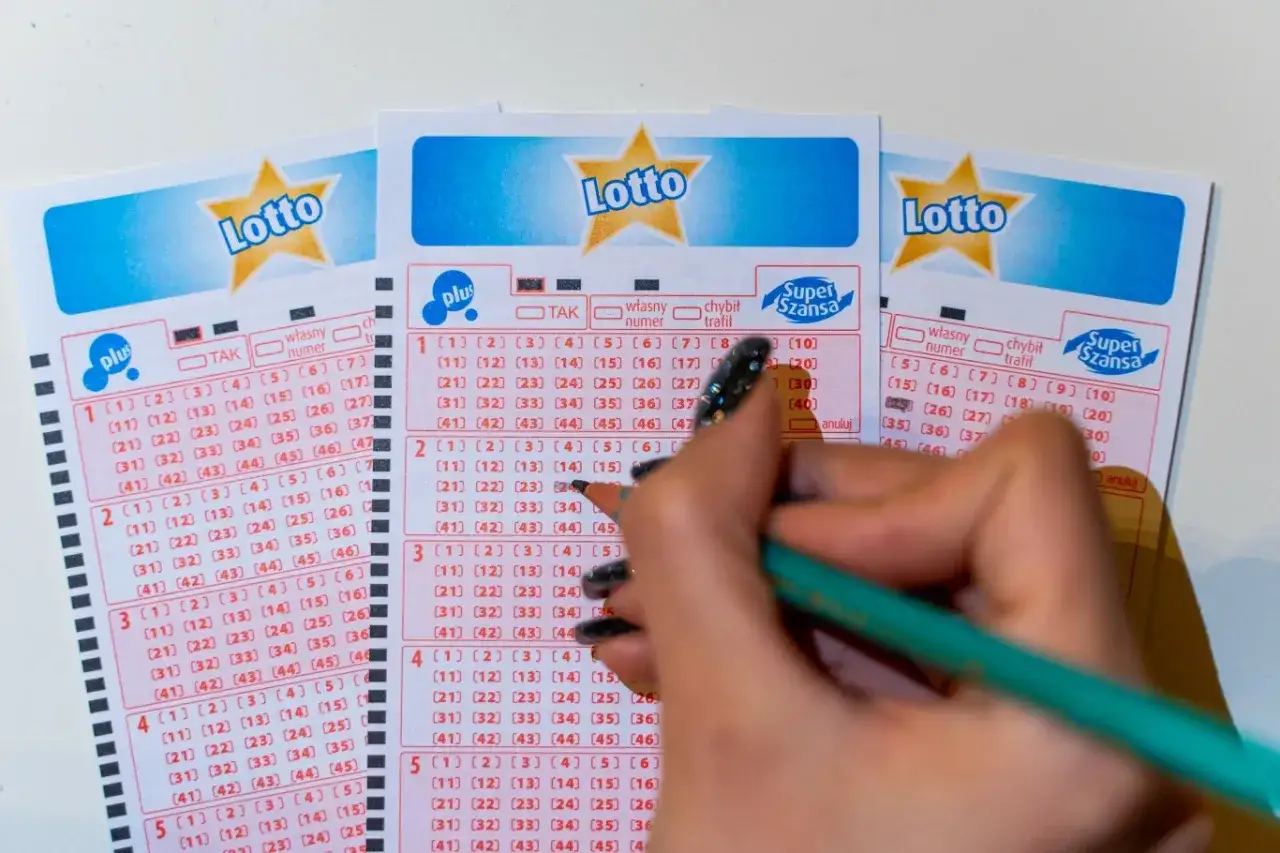 Ręka zaznacza liczby na kuponach Lotto. Czy systemowe granie w lotto czy matematycznie zwiększa szanse?