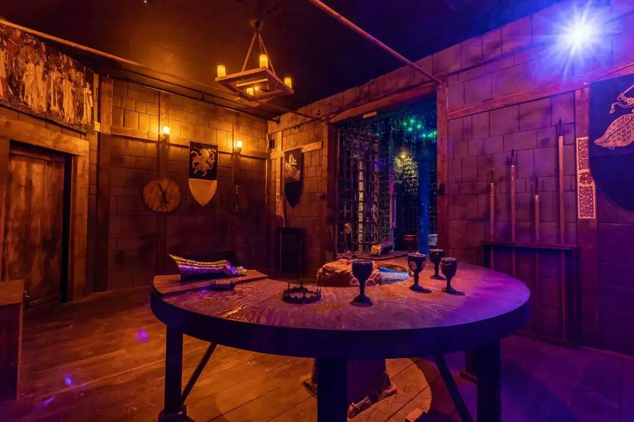 Pomysł na to, jak stworzyć własny escape room w domu dla nastolatków: sala w stylu zamkowym z tajemniczymi przedmiotami na stole i kratą w tle.