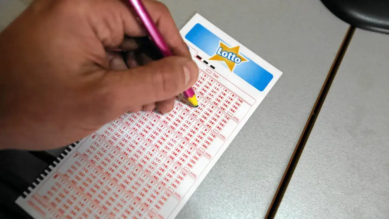 Ręka z ołówkiem zaznacza liczby na kuponie Lotto. Czy to będzie multi multi sprawdź kupon i wygraj!