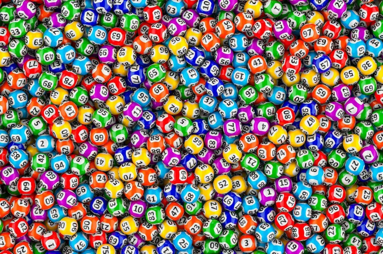 Mnóstwo kolorowych kul do gry w bingo, każda z nadrukowaną liczbą. Los kaskady wydrukowany przez terminal.