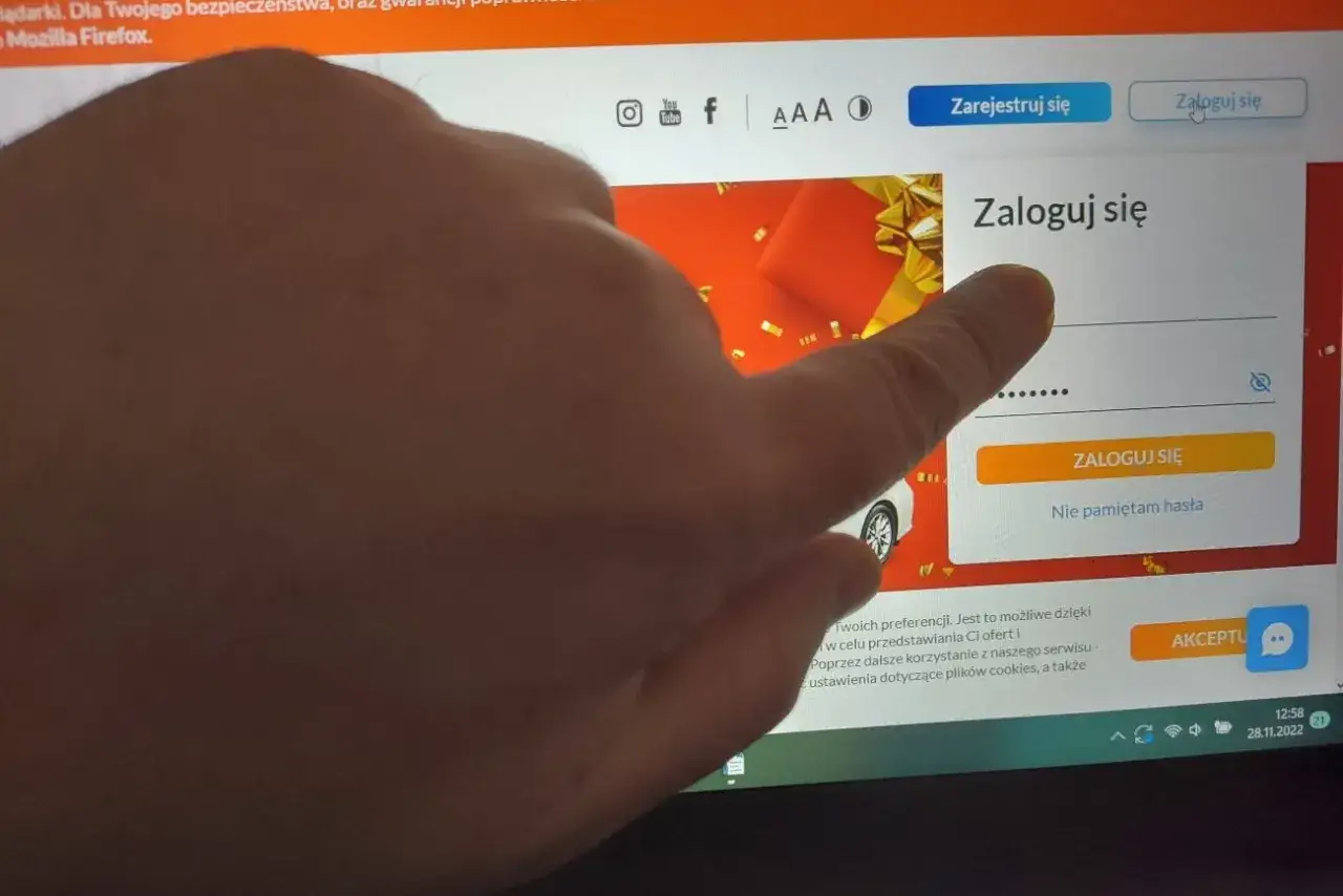 Palec wskazuje pole logowania na stronie, gdzie można sprawdzić, czy aplikacja lotto jest bezpieczna.