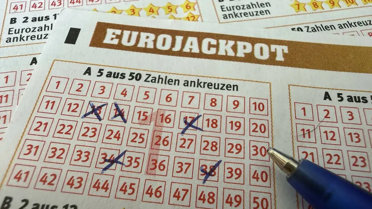 Kupon loterii świątecznej Eurojackpot z zaznaczonymi liczbami. Długopis wskazuje na pole wyboru.