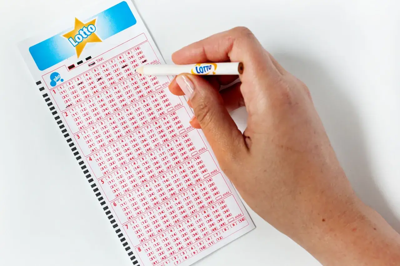 Dłoń zaznacza liczby na kuponie Lotto. Pytanie 