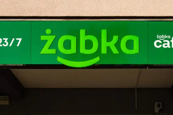Zielony neon sklepu Żabka z napisem "23/7" i logo "żabka cafe".
