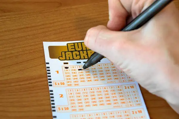 Ręka wypełnia kupon Eurojackpot. Syndykat w Eurojackpot, koszty podziału kuponu systemowego na 10 osób.
