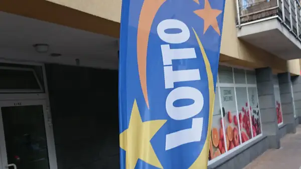 Niebieska flaga z logo LOTTO i gwiazdami. Szukasz rankingu zdrapek lotto z największym prawdopodobieństwem trafienia?