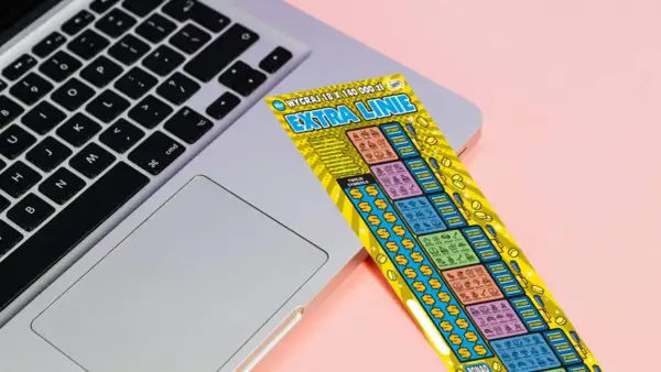 Zdrapka "Extra Linie" leży na laptopie. Czy uda się znaleźć wygrywające symbole i dodatkowe linie?