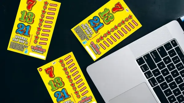 Żółte zdrapki Lotto leżą obok laptopa. Czy sprzedawca w kolekturze wie w której zdrapce jest wygrana?