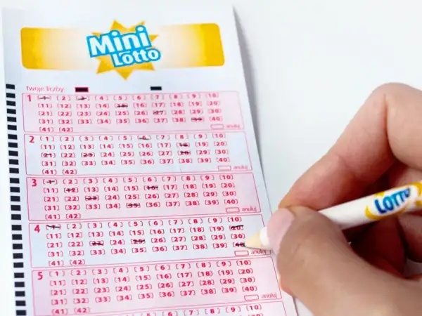 Ręka zaznacza liczby na kuponie Mini Lotto. To pokazuje, jak sprawdzana jest uczciwość bębna i certyfikaty maszyn losujących.