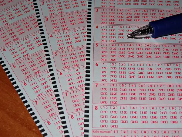 Zdrapki lotto z polami do zaznaczenia liczb i długopisem.