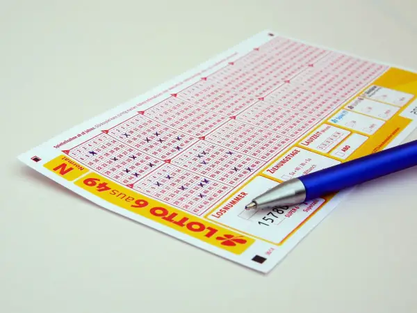 Kupon do gry Lotto z zaznaczonymi liczbami i długopisem. Zastanawiasz się, jak zablokować konto na stronie Lotto samowykluczenie na stałe?
